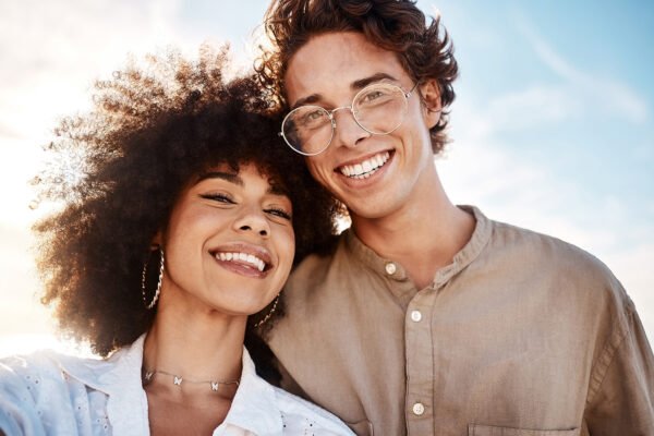 Portrait of a young mixed race couple enjoying a day at the beach looking happy and in love.